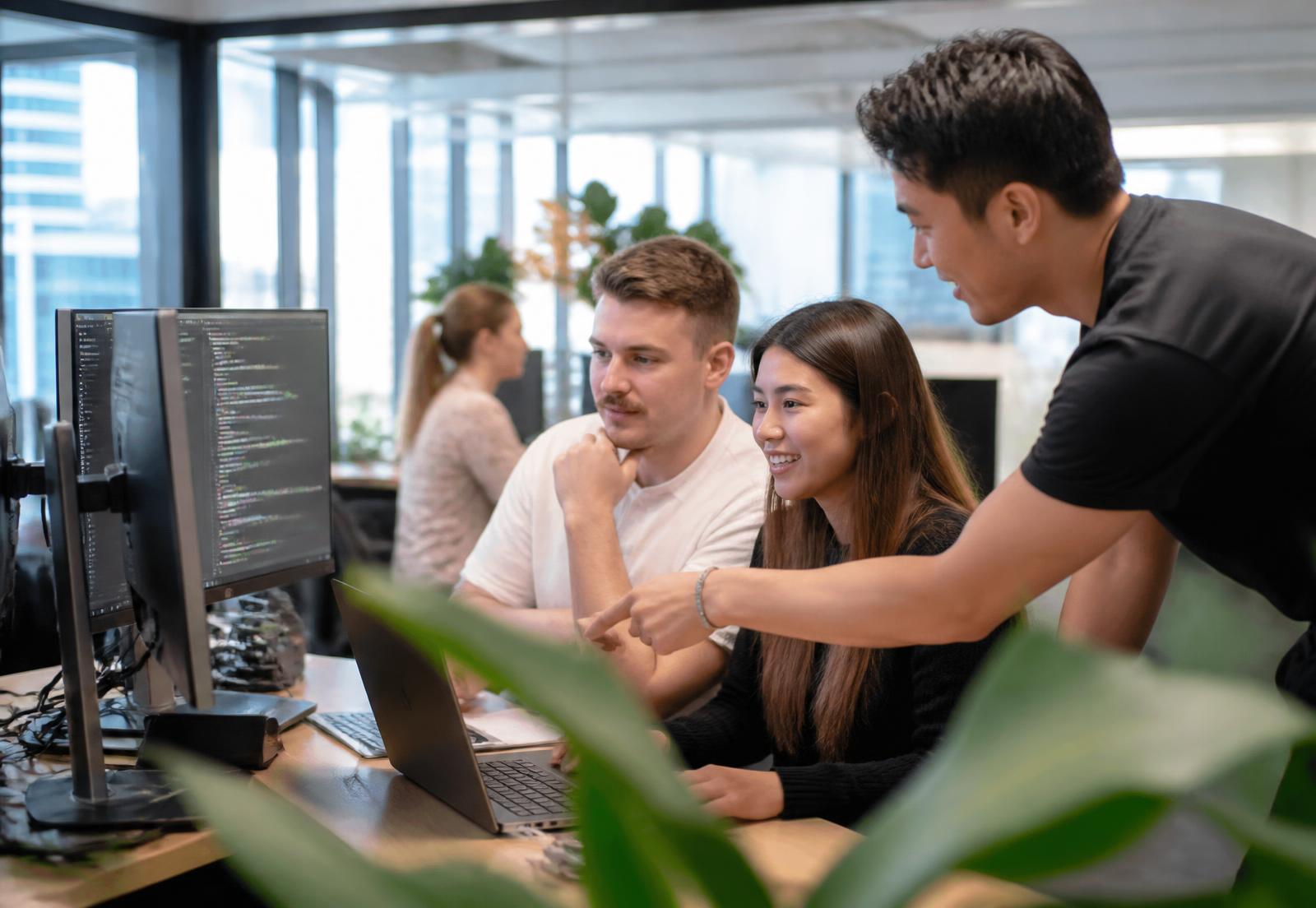 Graduate software engineers being mentored by a senior colleague